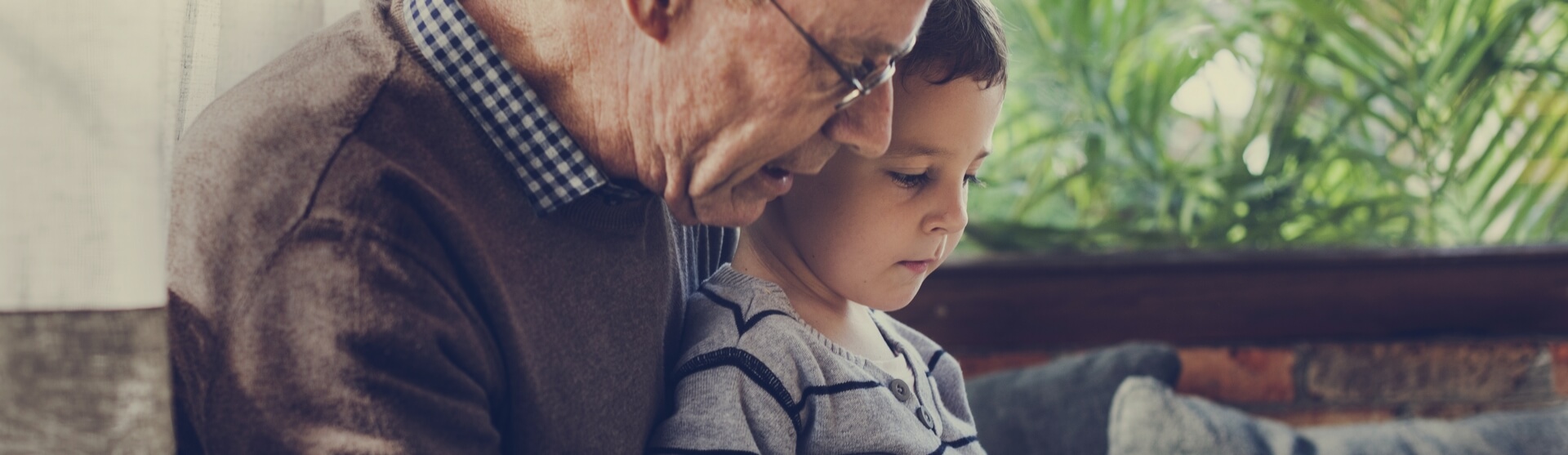 A grandfather reading a book with his grandson.