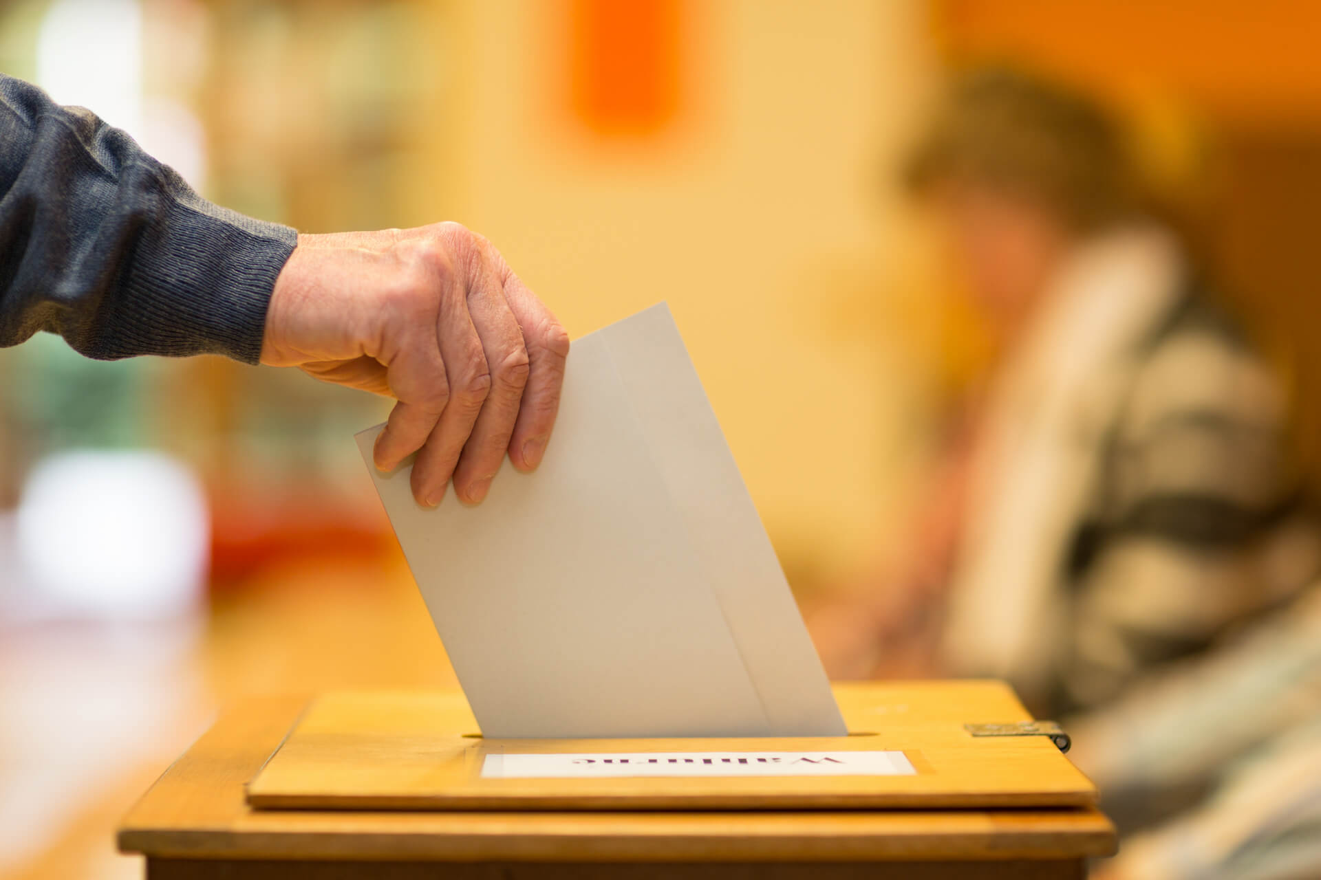 A man putting a ballot paper into a ballot box.